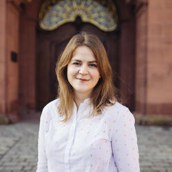 Annkathrin Wiltz lächelt und hat hellbraunes und schulterlanges Haar. Sie trägt eine weiße Bluse mit goldenen Punken.