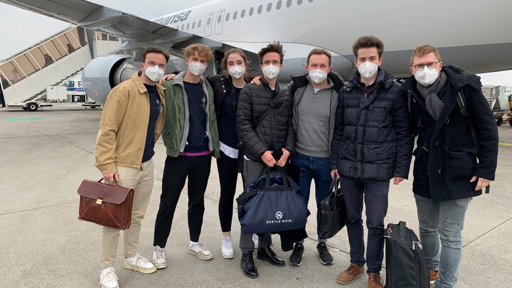 Eine Gruppe studierender mit Masken vor einem Flugzeug